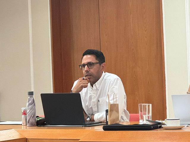 Rahim Hirji at a meeting table with a laptop, listening